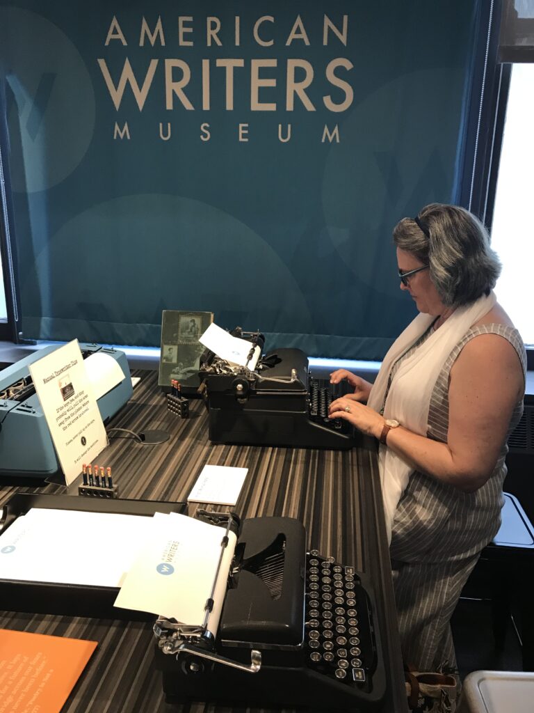 Picture of Marcella sitting at vintage typewriter at the American Writers Museum